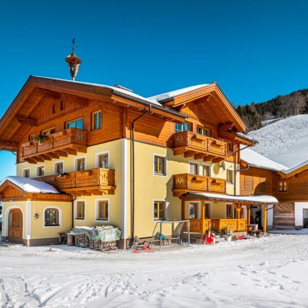 Außenansicht des Bauernhofs in einer schneebedeckten Berglandschaft.