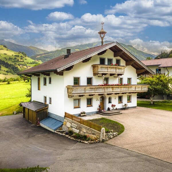 Das einladende Haus mit den Ferienwohnungen, umgeben von grünen Wiesen und einer malerischen Bergkulisse.