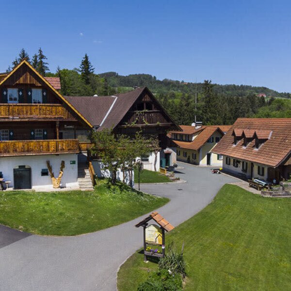 Der Bauernhof mit mehreren traditionellen Gebäuden, der Zufahrtsstraße und den umgebenden Grünflächen.