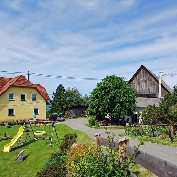 The exterior of the Farm House, featuring a green lawn with a children's playground, including a slide, swings, and a trampoline.