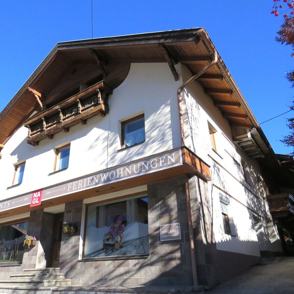 Die Außenansicht des Bauernhofs mit traditionellen Holzelementen, Balkon und der Aufschrift "Ferienwohnungen".