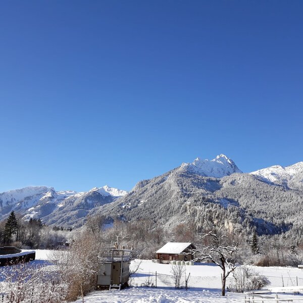 Blick auf die schneebedeckten Berge und die Winterlandschaft vom Bauernhof.