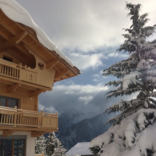 Außenansicht des Bauernhofs im Winter, mit Holzfassade, Balkonen und schneebedeckter Umgebung.