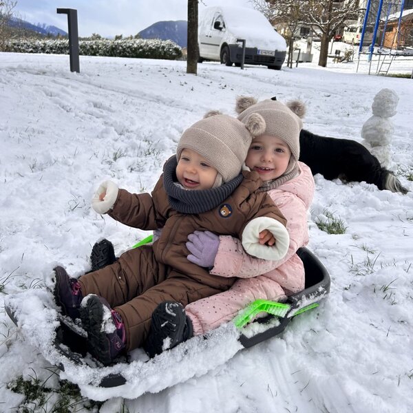 Kinder genießen den Schnee beim Rodeln auf dem Bauernhof.