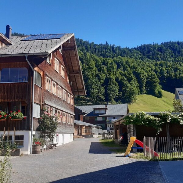 Der Bauernhof mit Holzfassade und Solaranlagen auf dem Dach bietet einen Kinderspielplatz sowie Aussicht auf die umgebenden Berge und Wälder.